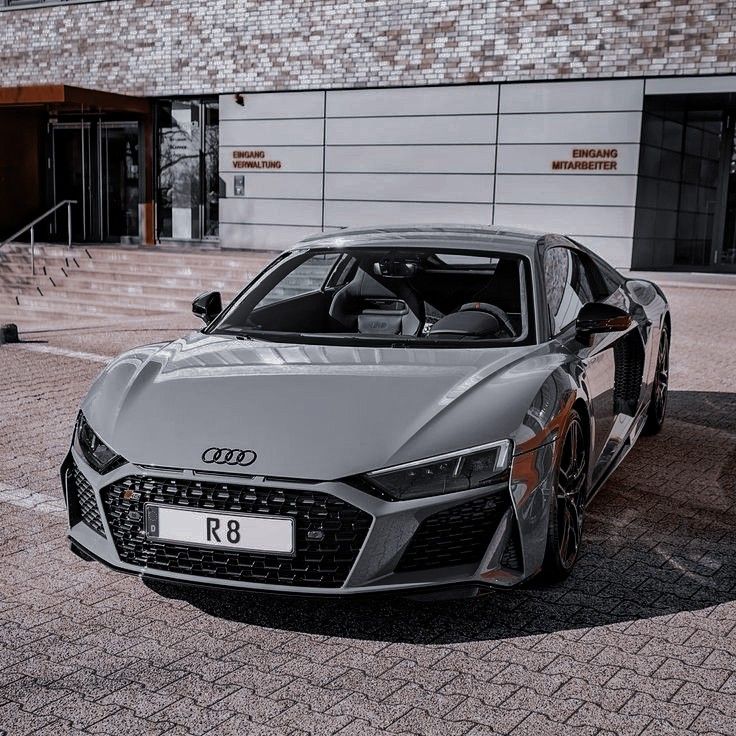 a grey sports car parked in front of a building