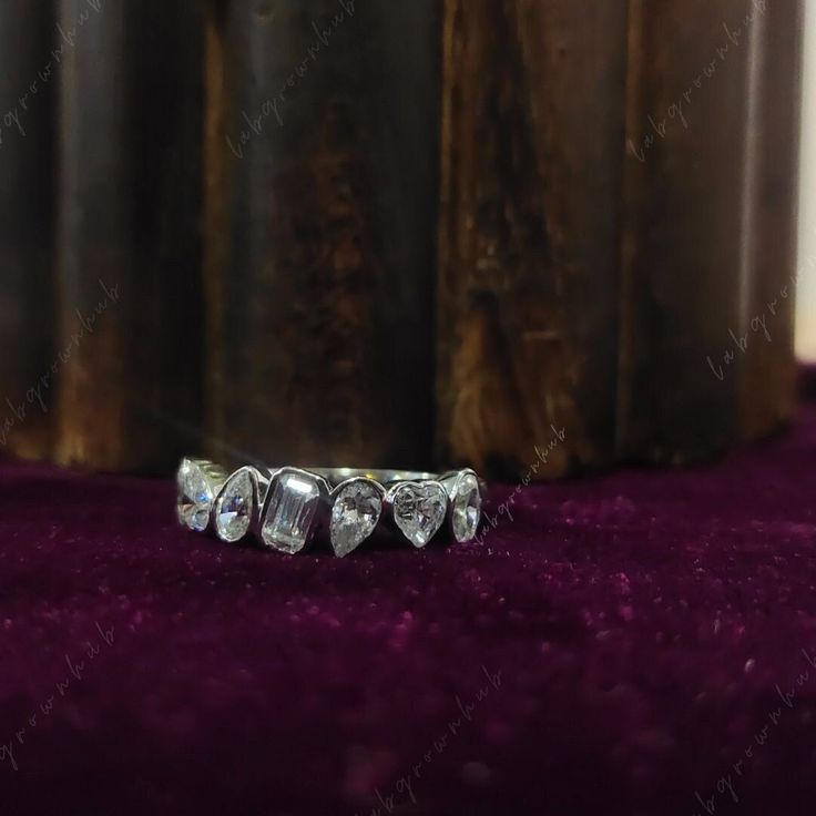 three stone ring sitting on top of a purple carpet