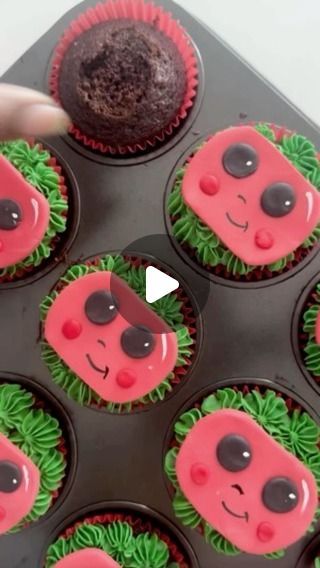 cupcakes decorated with pink and green frosting in a muffin tin being held by a person's hand