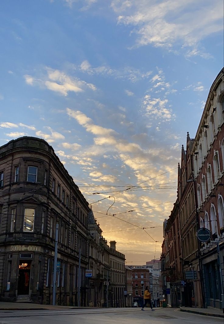 an empty street with buildings on both sides and blue sky in the background at sunset