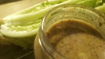 a jar filled with something next to lettuce on top of a wooden table