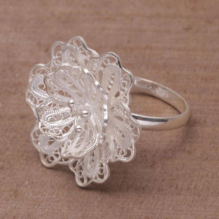 Working with local Balinese artisans Yuli follows in her mother's footsteps to help create beautifully elegant jewelry. She presents this sterling silver cocktail ring which features a handcrafted filigree crown in the shape of the waribang flower or hibiscus well-known for its wide petals and characteristically long stamens. Artisan Sterling Silver Rings With Intricate Design, Elegant Flower Ring Stamped 925, Traditional Filigree Ring For Anniversary, Sterling Silver Filigree Ring For Formal Occasions, Ornate Sterling Silver Filigree Ring, Sterling Silver Flower Ring With Intricate Design For Wedding, Wedding Sterling Silver Flower Ring With Intricate Design, Silver Artisan Rings With Intricate Design, Wedding Flower Ring In Sterling Silver With Intricate Design