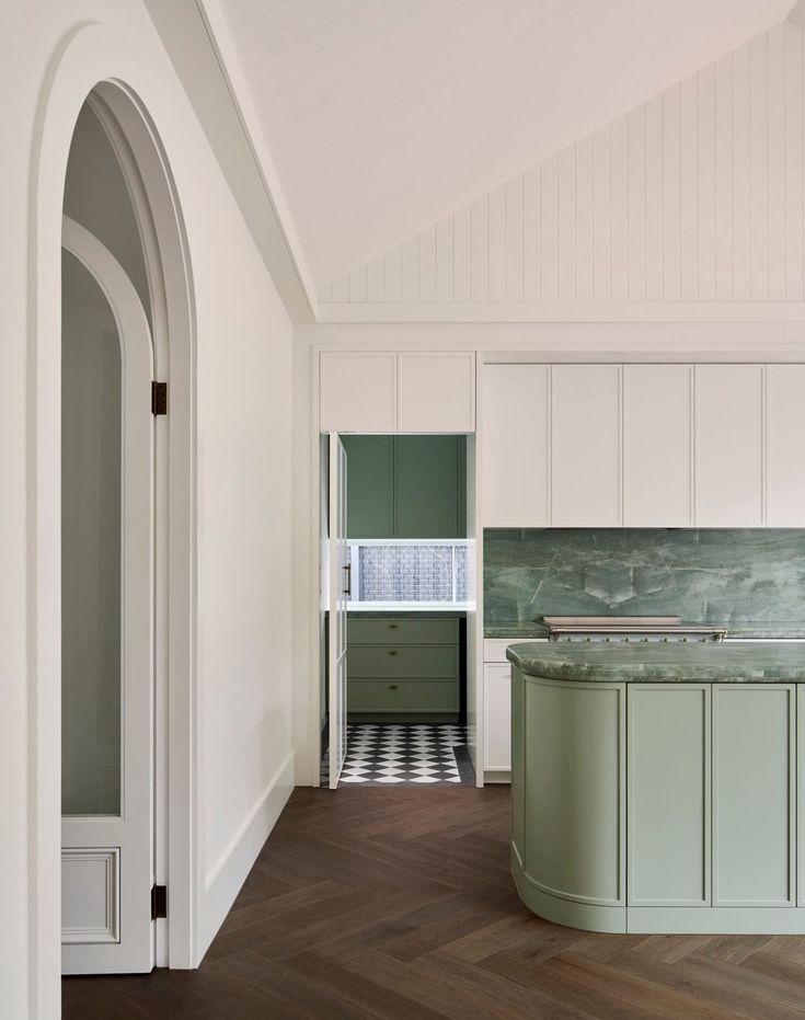 an empty kitchen with green cabinets and marble counter tops