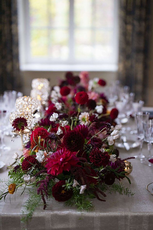 the table is set with wine glasses and red flowers in vases, along with silverware