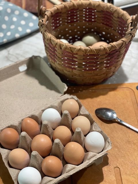 an open carton of eggs sitting on top of a table next to a basket