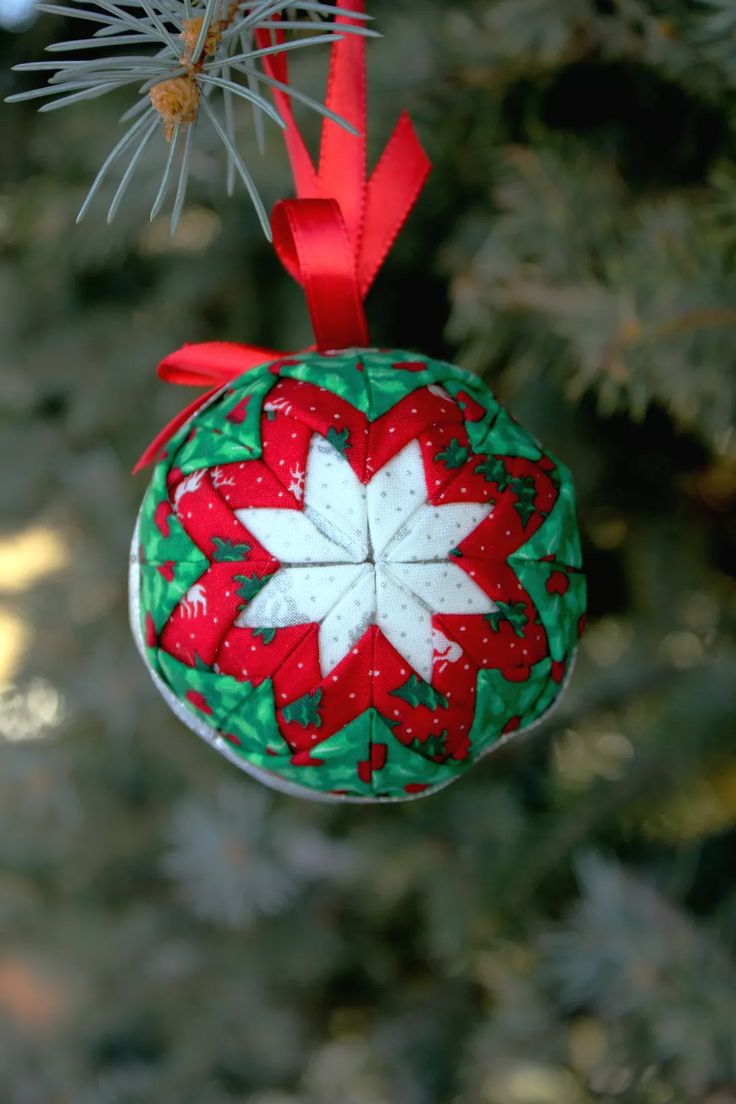 an ornament hanging from a christmas tree decorated with red, white and green fabric