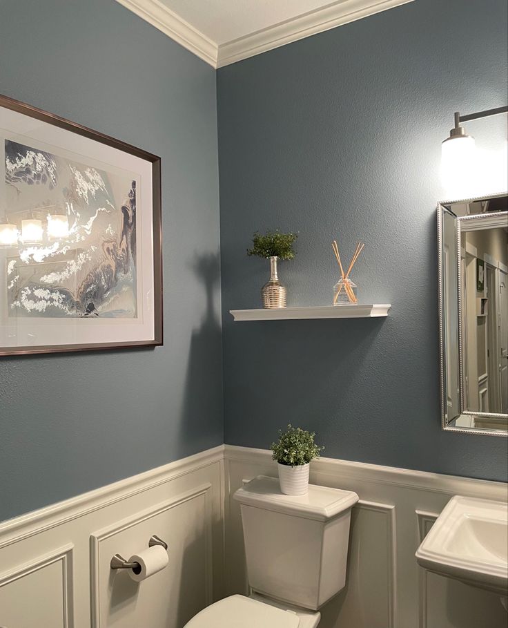 Blue bathroom with wainscoting and crown molding Bathroom 2 Color Walls, Bathroom Blue And Grey, Light Blue Wall Bathroom, Greyish Blue Bathroom, Bathroom Inspo Wall Color, Light Blue Walls With Accent Wall, Light Blue Restroom Ideas, Country Blue Bathroom Ideas, Restroom Wall Color Ideas