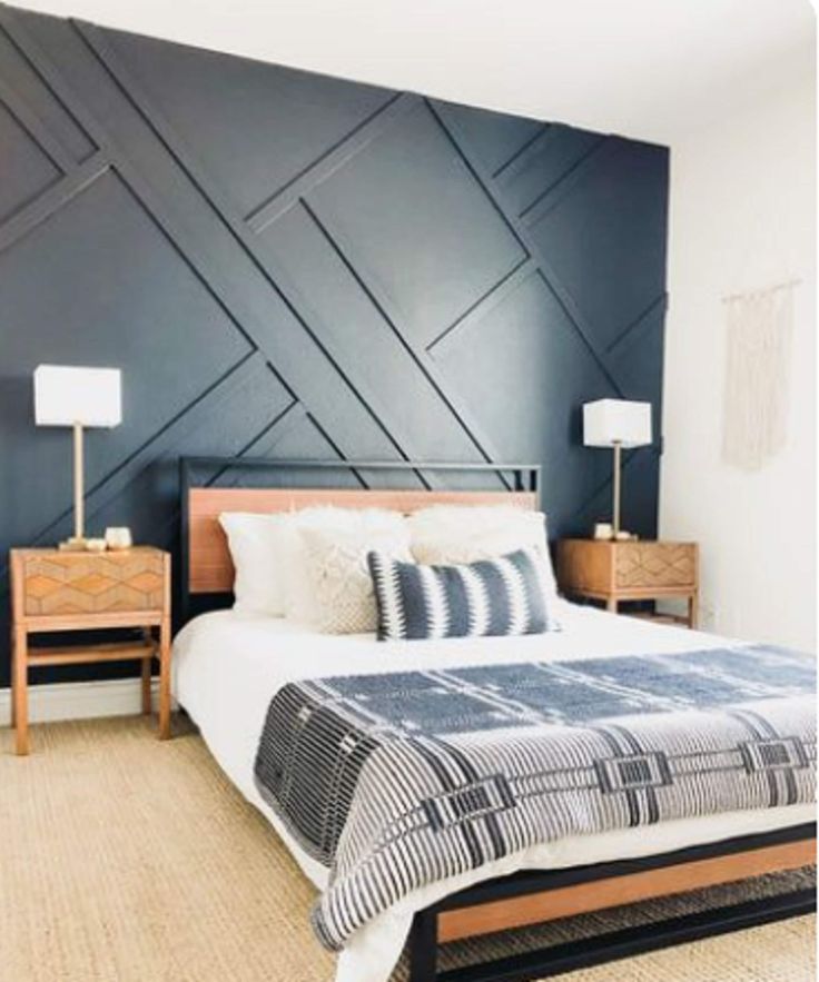 a bedroom with a bed and two nightstands in front of a wall painted black