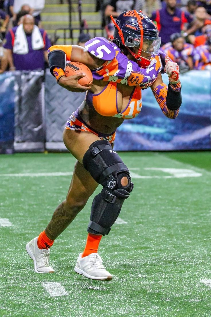 a football player running with the ball in his hand and wearing an orange helmet on