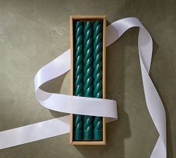 two green candles in a wooden box with white ribbon