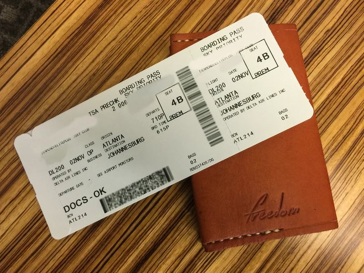 a brown leather wallet sitting on top of a wooden table next to a boarding pass