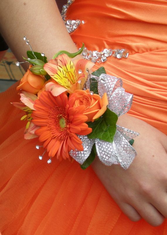 a woman in an orange dress holding a bouquet of flowers on her arm and the bridesmaid's wrist