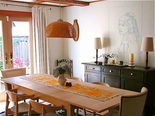 a dining room table with chairs and a vase on top of it in front of a sliding glass door