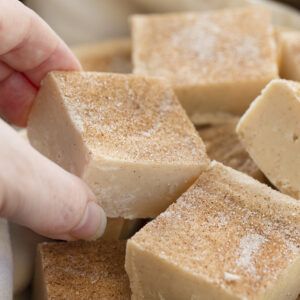 someone is picking up some sugar from a bowl full of cubed cake batters