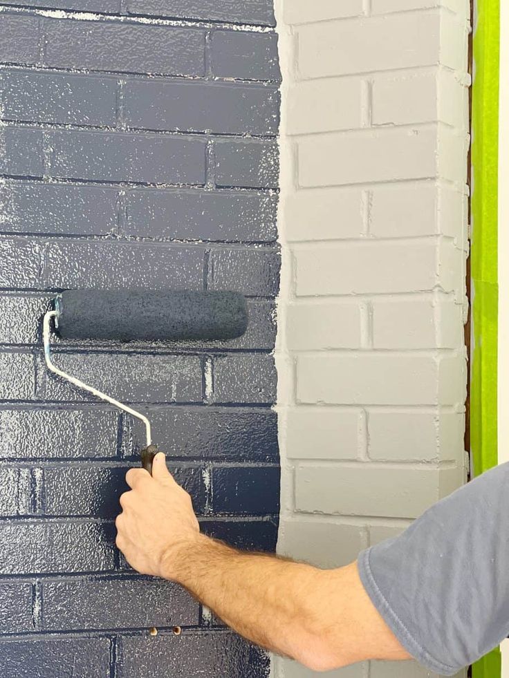 a man painting a brick wall with a paint roller