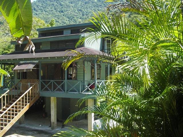 a green house surrounded by trees and mountains in the background with stairs leading up to it