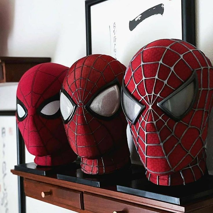 three spider - man masks sitting on top of a dresser