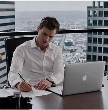 a man sitting at a desk in front of a laptop computer and writing on a piece of paper