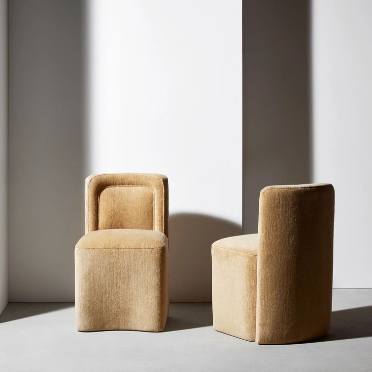 two chairs sitting next to each other in front of a white wall and flooring