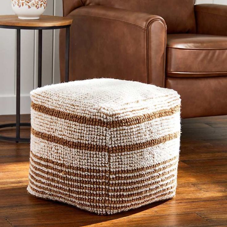 a brown and white ottoman sitting on top of a wooden floor next to a chair