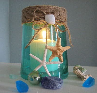 a glass jar filled with sand and starfish sitting on top of a white table