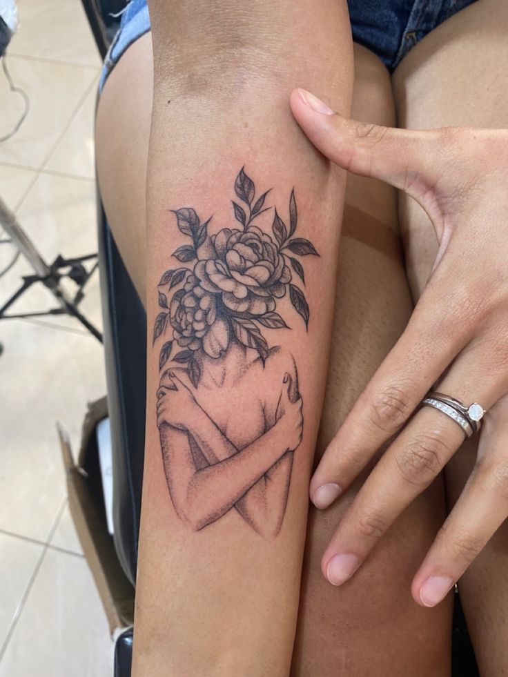 a woman's arm with flowers on it and a girl holding her hand up