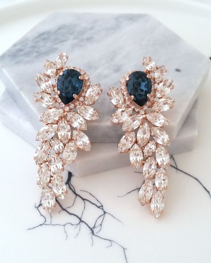 two pairs of blue and white crystal earrings on a marble surface with a marble slab in the background