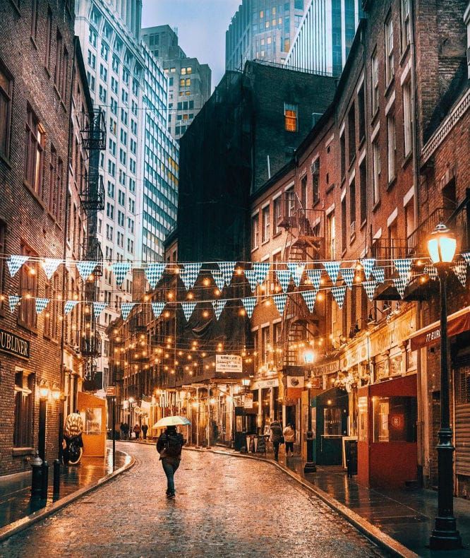 a person with an umbrella walking down the street in front of some buildings at night