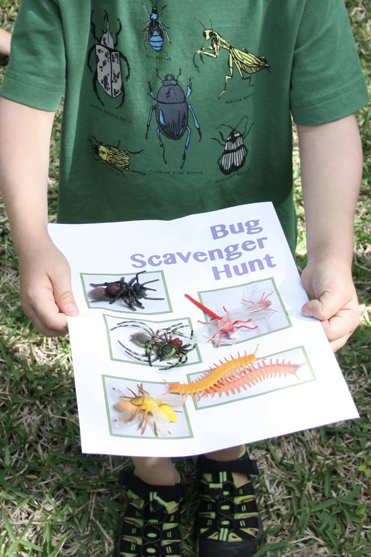 a young boy holding up a bug scavenger hunt poster