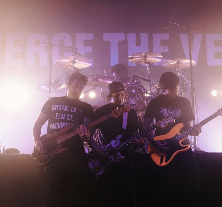 three young men playing guitars on stage with the words rage of the eve in front of them