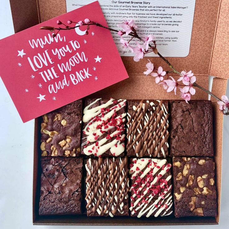 a box filled with brownies covered in frosting and sprinkles next to a card