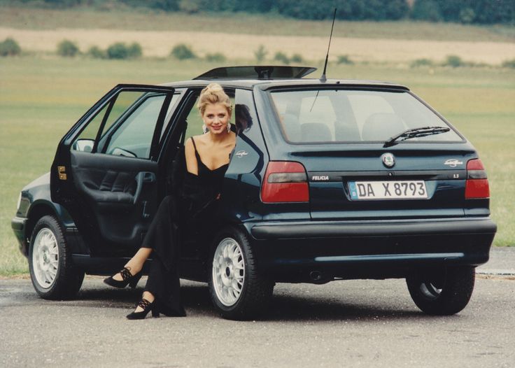 a woman sitting in the door of a black car