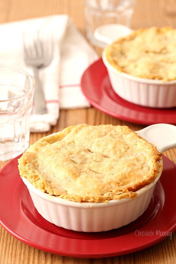 two pies sitting on top of red plates next to forks and silverware,