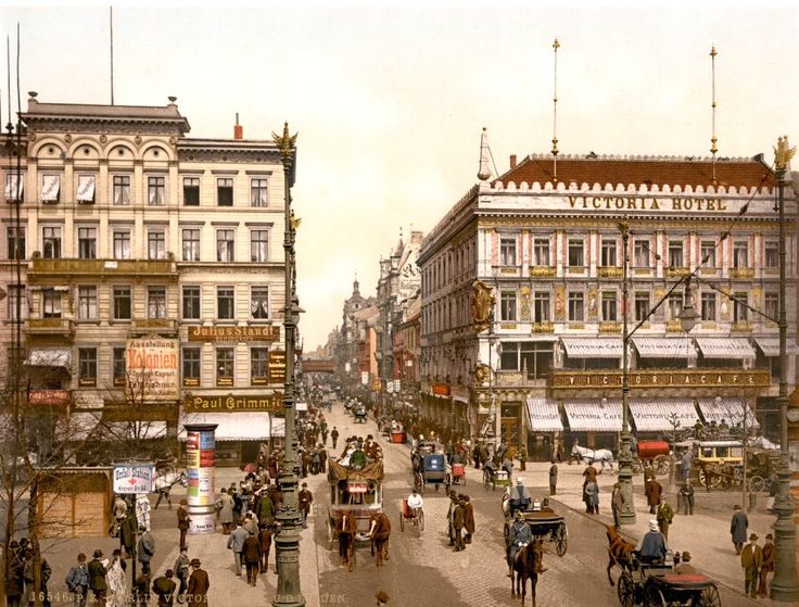 an old photo of people riding horses and carriages down the street in front of buildings