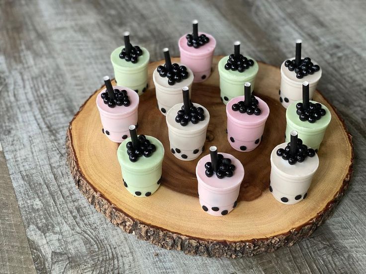 there are many small cups with blackberries in them on a wooden tray and one is decorated with polka dots