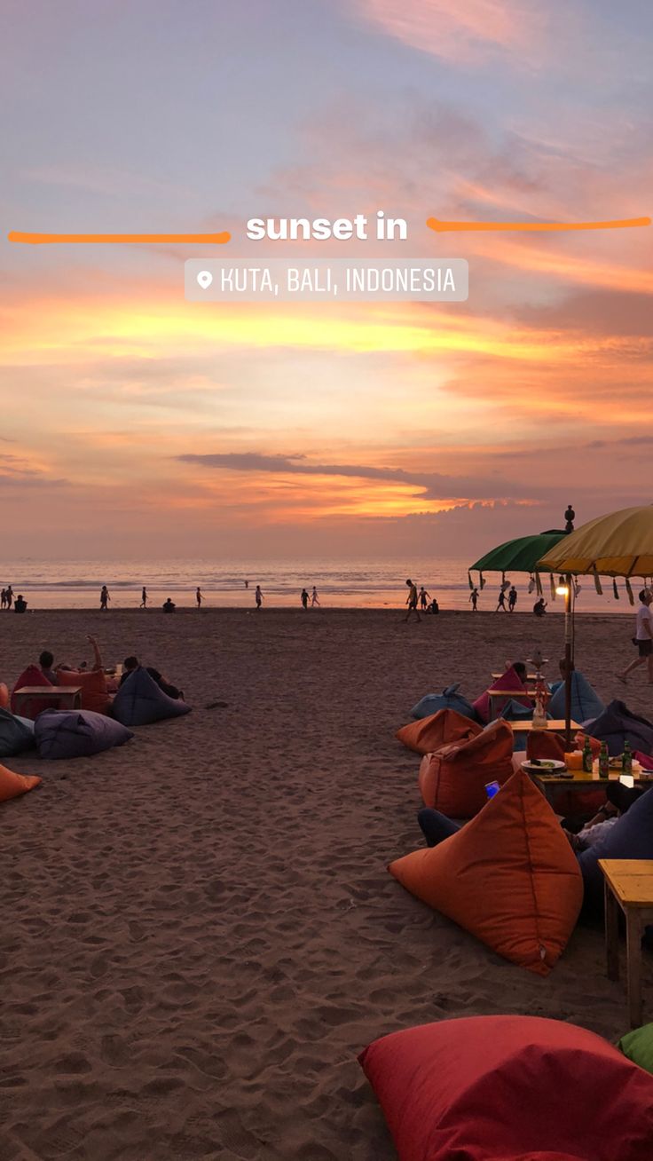 people laying on the beach at sunset with umbrellas and chairs in the foreground