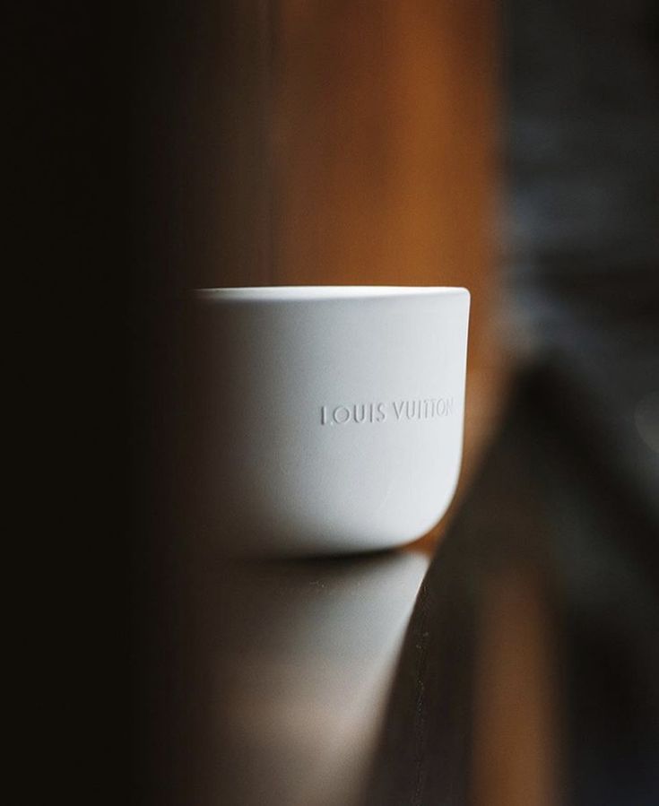 a white bowl sitting on top of a wooden table next to a wall with the word louis vuittre written in it