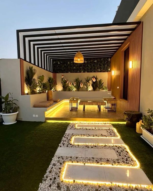 an outdoor area with lights and plants on the grass, in front of a house