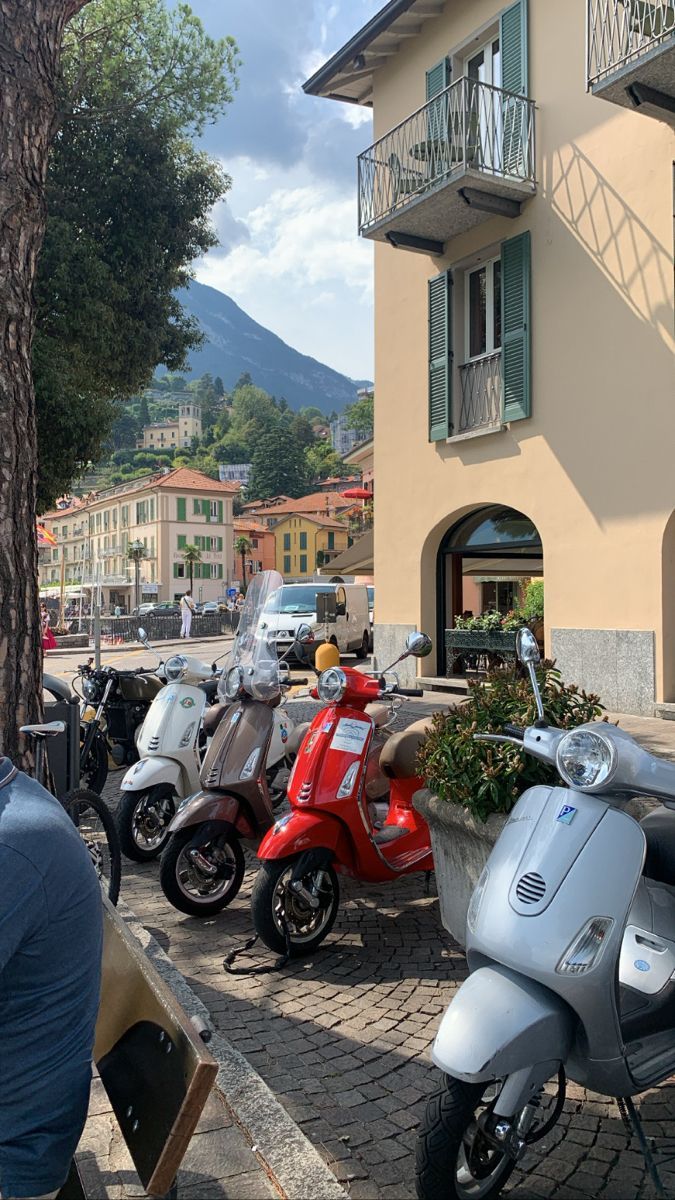 several scooters parked in front of a building with balconies on it