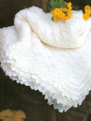 a white crocheted shawl with yellow flowers on it