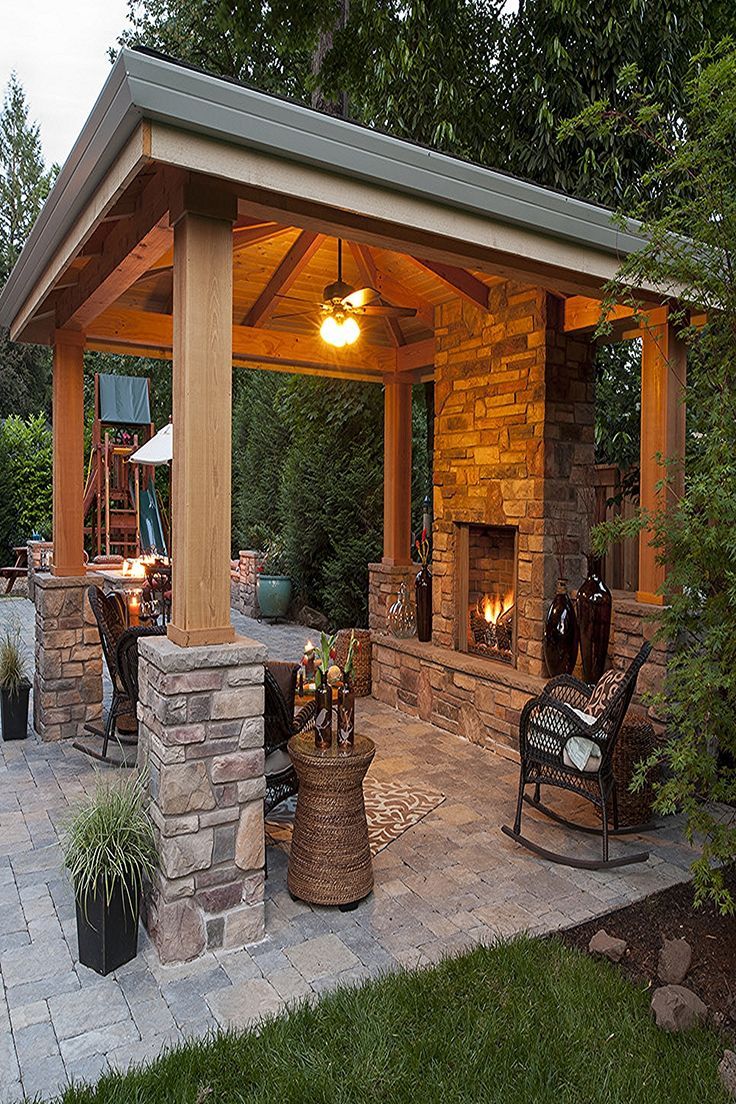 an outdoor patio with stone fireplace and seating area