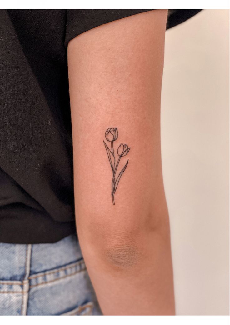 a woman's arm with a small flower tattoo on the left side of her arm