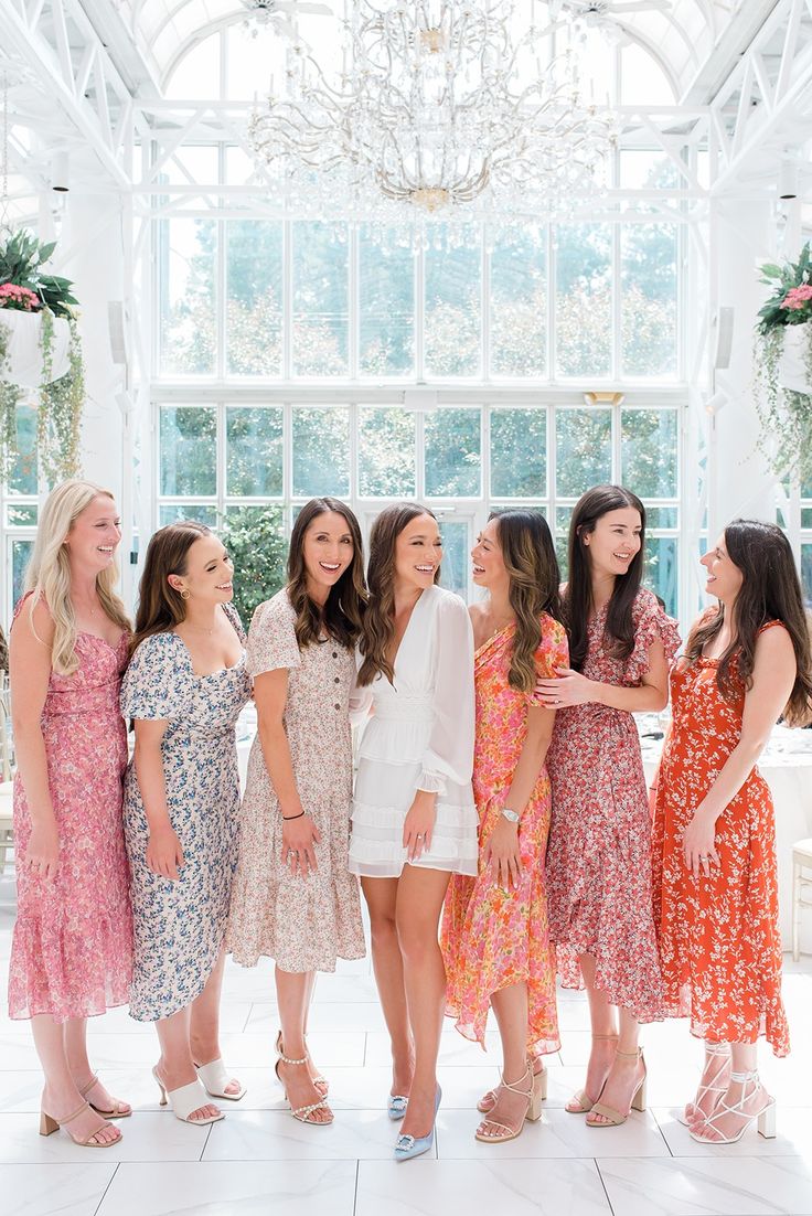 a group of women standing next to each other in front of a chandelier