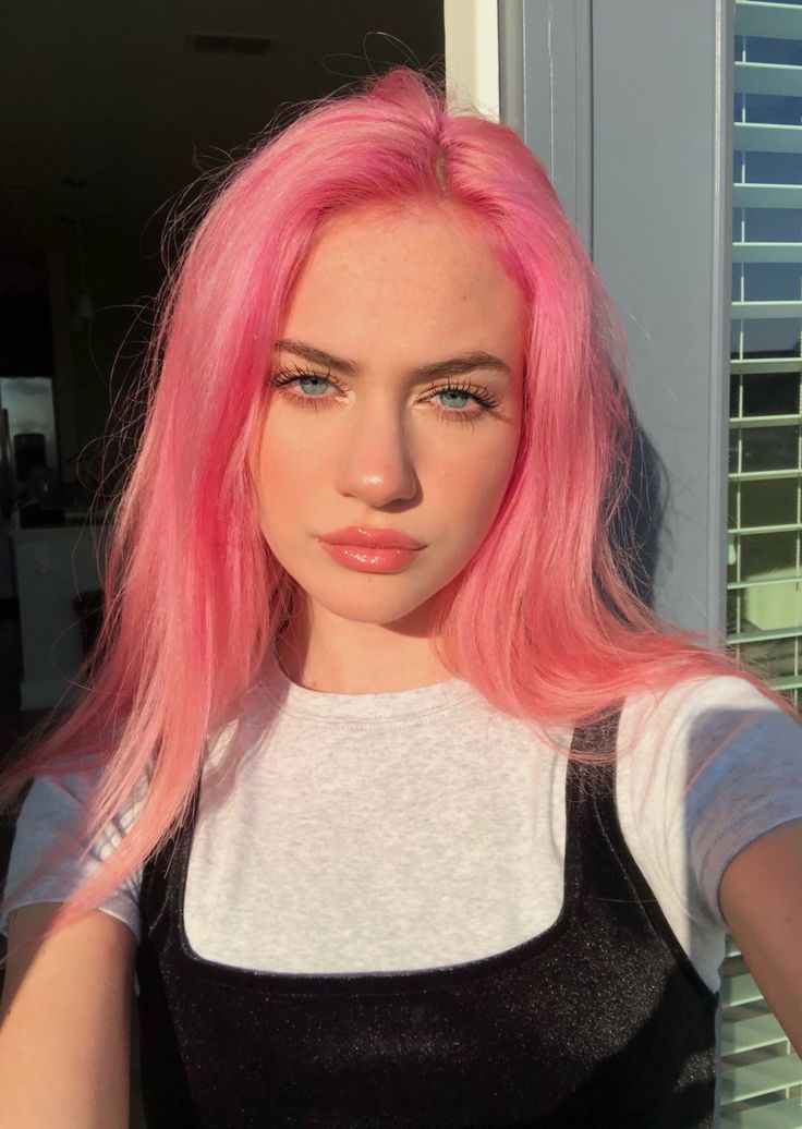 a woman with pink hair is posing for the camera