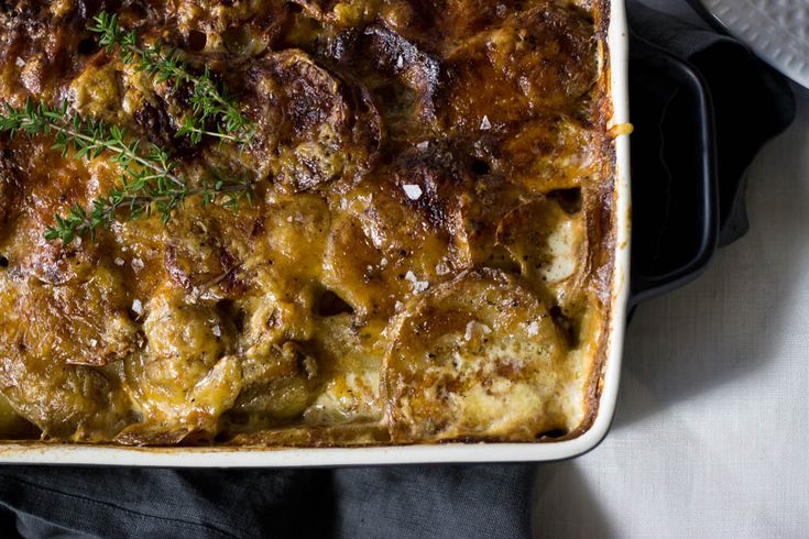 a casserole dish with meat and vegetables in it on a white table cloth