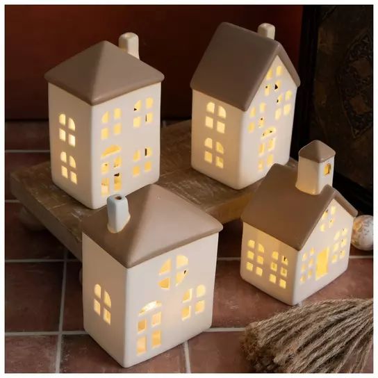 three lit up houses sitting on top of a tile floor next to a rug and wall