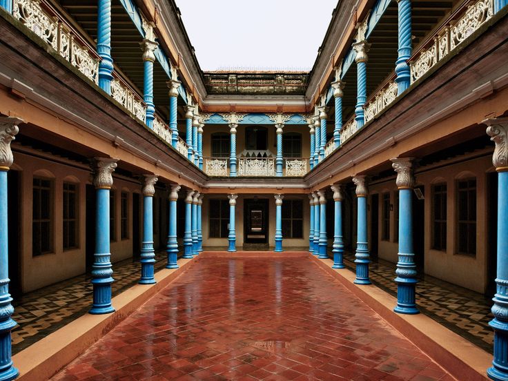 an empty building with blue columns and red tile flooring in the foreground, looking up into the sky