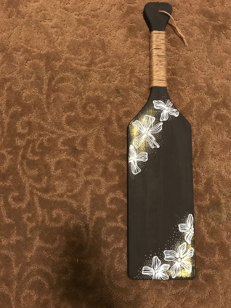 a wooden paddle with flowers painted on it sitting on a carpeted floor next to a wall