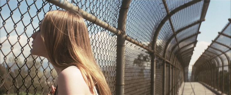 a young woman standing next to a fence