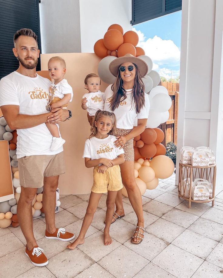 a man, woman and two children standing in front of balloons with gold letters on them